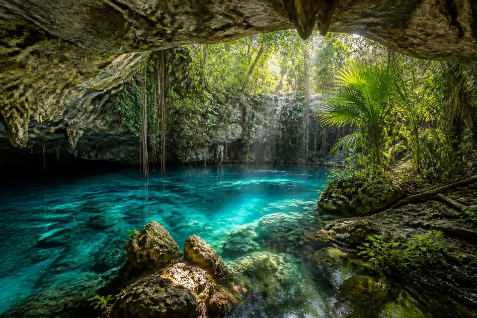 Cenote de águas azul-turquesa cercado por vegetação tropical