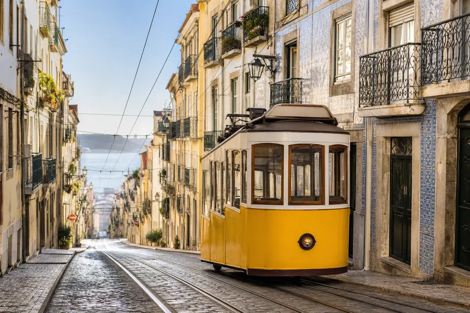 Bonde amarelo em uma rua histórica de Lisboa com fachadas de azulejos